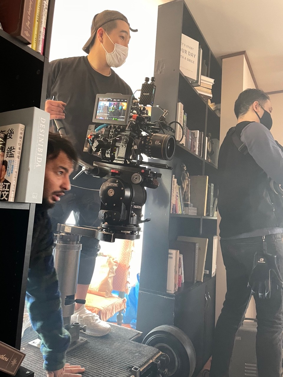A small film crew gathered around the camera